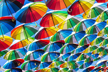 Fototapeta premium Colorful umbrellas Blue, green, red, rainbow umbrellas background Street with umbrellasin the sky Street decoration.