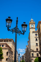 Fototapeta na wymiar Beautiful street lamp and the clock tower of an antique building at Zamora Street in Salamanca city center