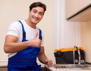 Young repairman working at the kitchen