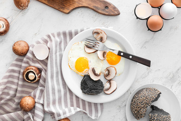 Plate with fried eggs and mushrooms on white background