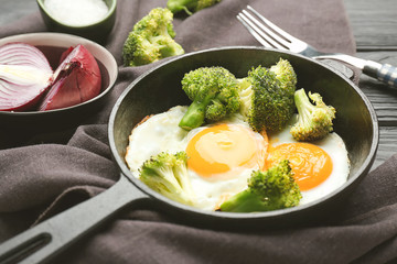 Frying pan with cooked eggs and vegetables on table