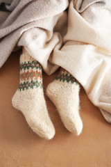 Fototapeta na wymiar Legs of woman in knitted socks and plaid on color background
