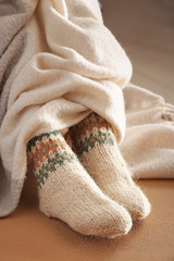 Fototapeta na wymiar Legs of woman in knitted socks and plaid on color background