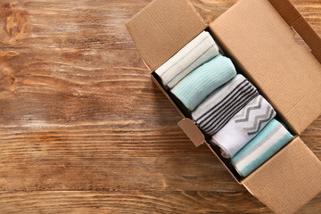 Box with different socks on wooden background