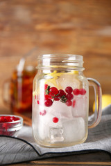 Fototapeta na wymiar Mason jar with ice cubes, cranberries and lemon on table