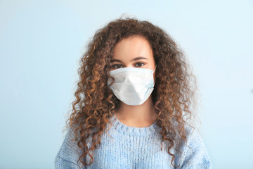 Young woman with protective mask on light background. Concept of epidemic