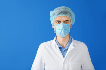 Male doctor with protective mask on color background. Concept of epidemic