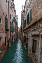 Fototapeta na wymiar Narrow Canal mirroring the surrounding Houses, Venice/Italy