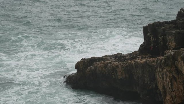 Water wave hitting the rocks cloudy day