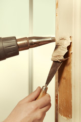 Man at home removing havy layer of old paint from door
