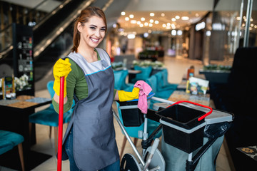 Beautiful young woman cleaning at shopping mall. Cleaning concept. - obrazy, fototapety, plakaty