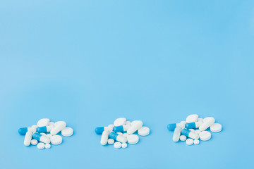 Assorted pharmaceutical medicine pills, tablets and capsules and bottle on blue background. Copy space for text