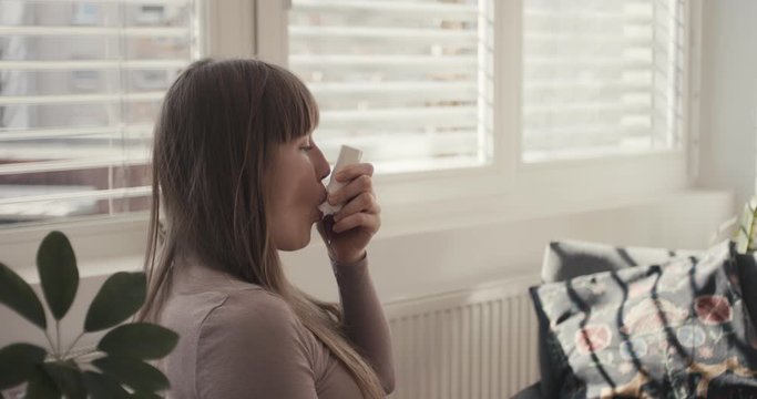 Woman inhales asthma inhaler virus coronavirus at home quarantine from behind