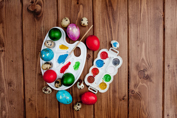 Colored eggs and paint on a wooden table, Easter background