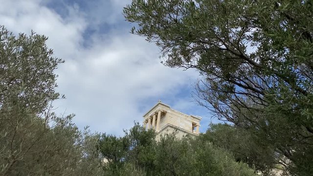 View to Parthenon antique temple with columns through trees from downhill park on Acropolis of Athens Greece