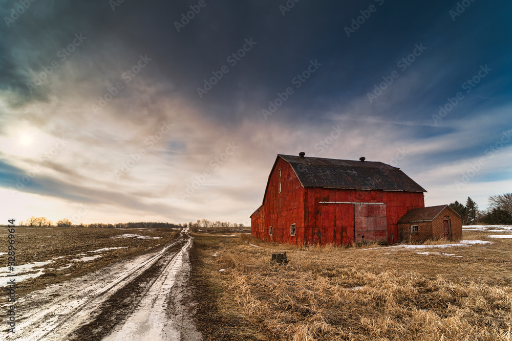 Wall mural stunning dramatic sunsets in rural farm country with barns and cold fields with rainbow.
