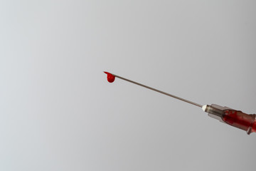 Syringe with a blood sample. A drop of blood at the end of the needle. Blood chemistry. Blood test...