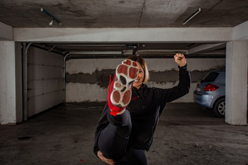 Portrait of beautiful brunette athlete with black hoodie posing in a garage