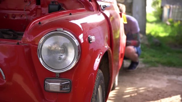 Close up of headlight of old red classic car. Headlight have chrome polished bezel. Turn signal under headlight lamp of vintage automobile.
