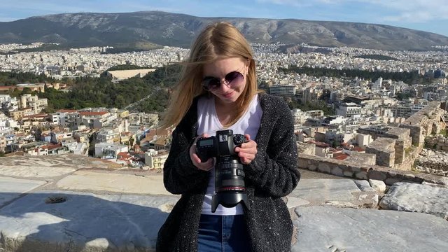  A pretty blonde woman photographer look through took photos at camera at the Acropolis hill