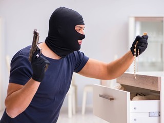 Robber wearing balaclava stealing valuable things