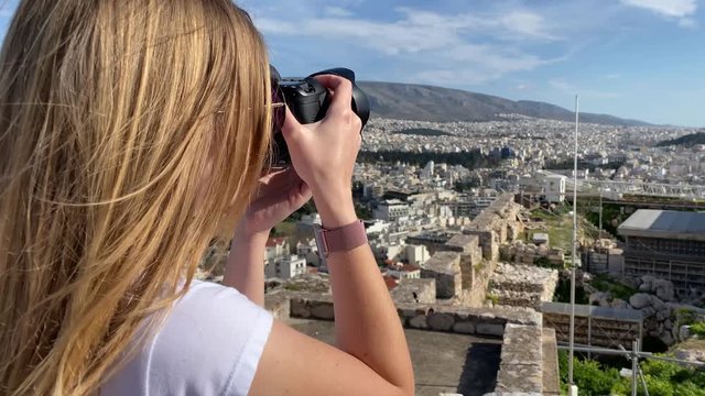 A pretty blonde woman photographer take pictures over Athens from the Acropolis hill