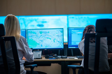 Female security guards working in surveillance room, monitoring cctv and discussing.