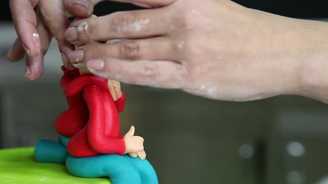 confectioner making figure from sugar paste fondant cake pastery