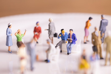 雑踏の中でベンチに座って会話する二人のビジネスマン