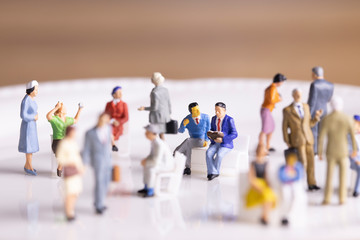 雑踏の中でベンチに座って会話する二人のビジネスマン
