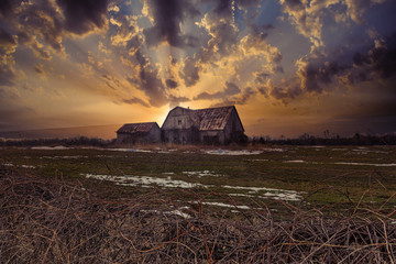 Stunning dramatic sunsets in rural farm country with barns and cold fields with rainbow. - 328973881