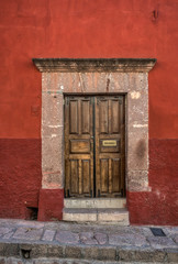 Fototapeta na wymiar A well kept old door with a stone frame and a red wall
