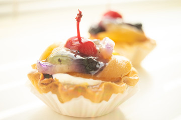 Cake basket with fruits and cherry on the table