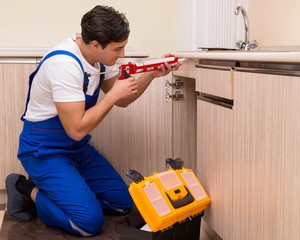 Young repairman working at the kitchen