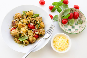 Gnocchi and chicken meatballs with pesto sauce, basil, tomatoes and nuts