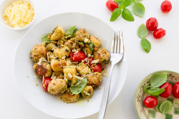 Gnocchi and chicken meatballs with pesto sauce, basil, tomatoes and nuts
