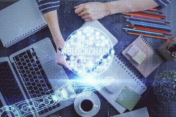 Cryptocurrency hologram, bitcoin, ico theme over hands taking notes background. Concept of blockchain. Multi exposure