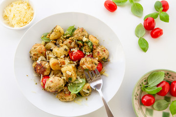 Gnocchi and chicken meatballs with pesto sauce, basil, tomatoes and nuts