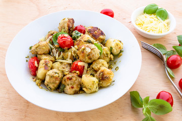 Gnocchi and chicken meatballs with pesto sauce, basil, tomatoes and nuts
