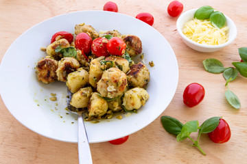 Gnocchi and chicken meatballs with pesto sauce, basil, tomatoes and nuts