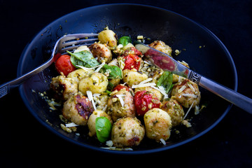 Gnocchi and chicken meatballs with pesto sauce, basil, tomatoes and nuts