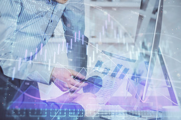 Double exposure of chart with businessman typing on computer in office on background. Concept of hard work.