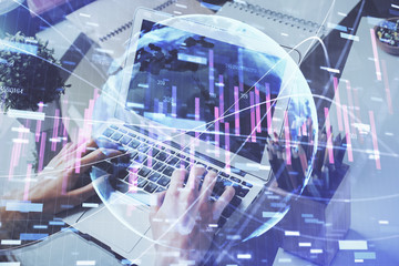 Double exposure of stock graph with businessman typing on computer in office on background. Concept of hard work.