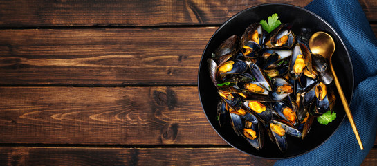 Close up of a olate with steamed mussels on dark wooden background