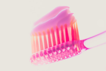 Pink plastic toothbrush with strawberry toothpaste on an isolated background.