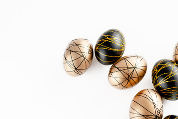 Easter golden decorated eggs in nest on white background . Minimal easter concept copy space for text. Top horizontal view, flatlay.