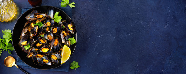 A plate with steamed mussels on dark blue background - obrazy, fototapety, plakaty