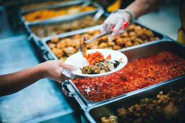 Volunteers help to draw food for the poor who are waiting to receive food in hunger.