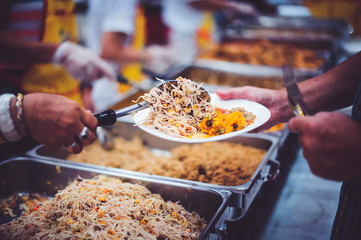 Volunteers help to draw food for the poor who are waiting to receive food in hunger.