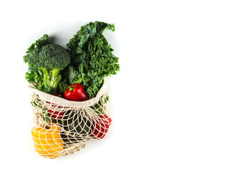 Eco friendly mesh bag with organic vegetables: Kale salad, broccoli, avocado, bell peppers on a white background. Zero waste concept. Healthy clean eating diet and detox. Top view, Copy space